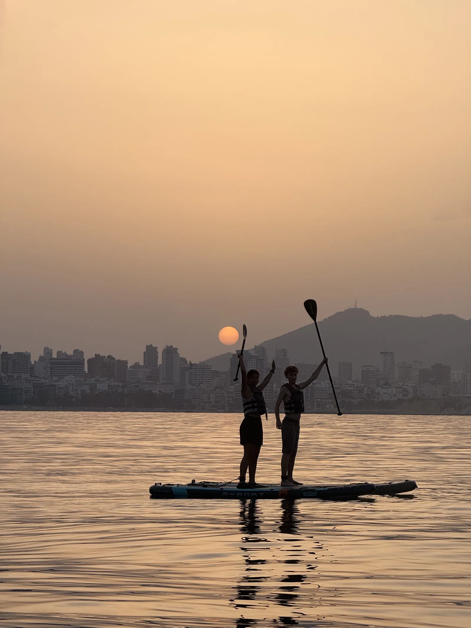 Pareja practicando paddle surf al amanecer en la playa de Benidorm